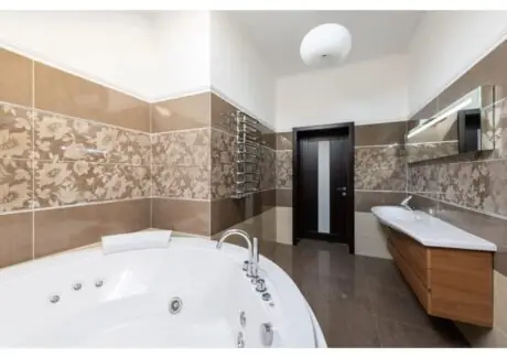 Spacious home bathroom interior with a white bathtub, sink, and tiled walls