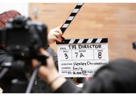 Film crew holding a clapperboard reading "The Director" on set