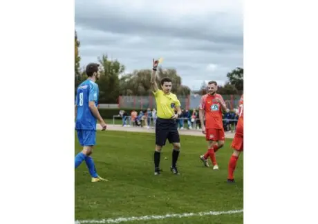 Soccer referee holding up a yellow card to a player during a match