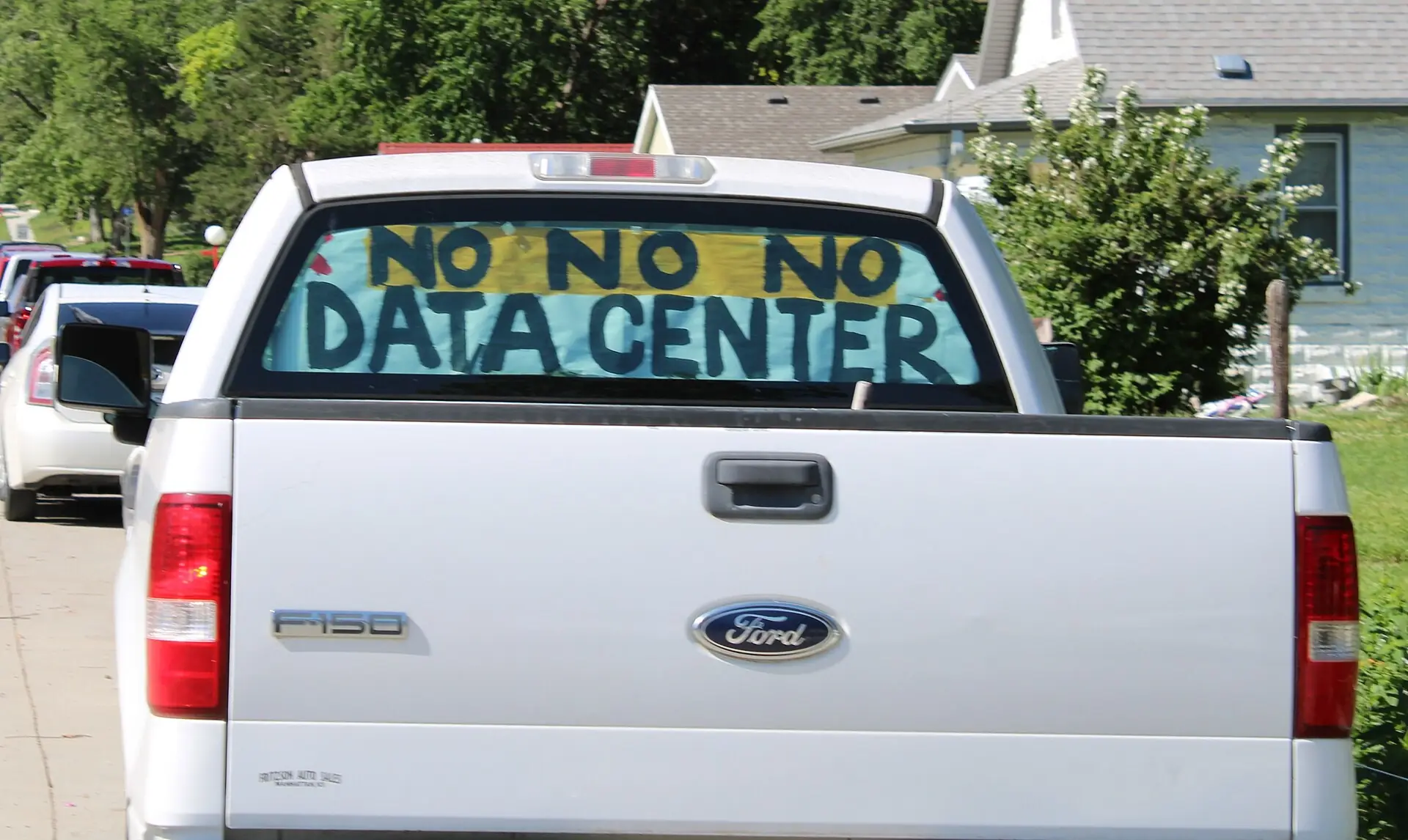 Hand-painted sign opposing a data centre displayed in a pickup truck