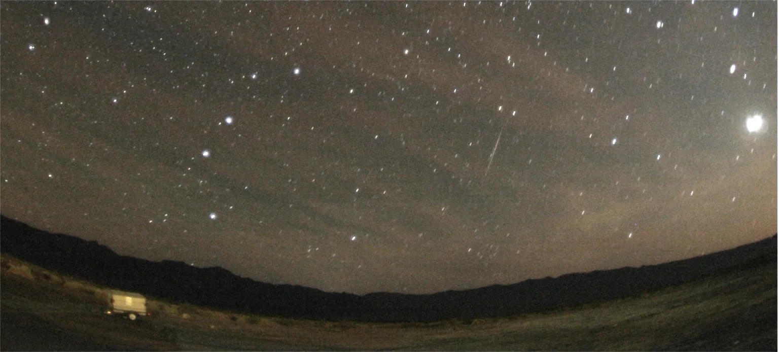 An Orionid meteor streak above a dark landscape in October 2007